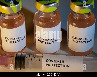 Impfstofffläschchen gegen Covid-19 mit Injektionsnadel und Schutz Gegen Coronavirus-Etikett in Nahaufnahme Stockfoto