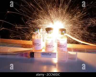 Impfstofffläschchen gegen Covid-19 mit Injektionsnadel und Schutz Gegen Coronavirus Label mit Feuerwerk Hintergrund Stockfoto