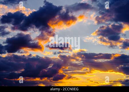 Ein sehr dramatischer Himmel voller Gelb, Blau und Orangen. Kontrastierende Wolken während des Sonnenuntergangs von der untergehenden Sonne beleuchtet. Hell gesättigt natürlich Stockfoto