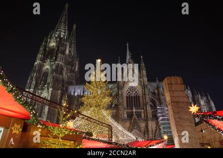 Nachtlandschaft und Blick aus dem niedrigen Winkel auf riesigen Weihnachtsbaum und Kölner Dom während Weihnachtsmarkt, Weihnachtsmarkt in Köln, Deutschland. Stockfoto