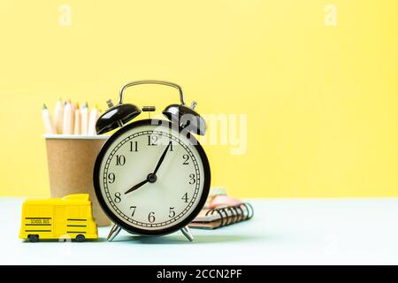 Back to School Banner mit schwarzem Wecker, Schulbus und Bleistift. Schulbedarf, andere Elemente in gelber Minze leerer Hintergrund mit Kopierraum. Stockfoto