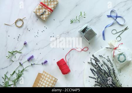 Selbst gemachte Lavendelsäckchen und aromatische Kräuterbadesalze machen. Lavendelblüten, frisch und trocken. Flache Laie auf weißem Marmor. Stockfoto