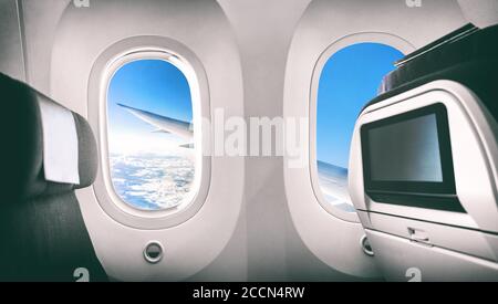 Flugzeug Passagiersitz Flugzeug Innenraum mit Fensteransicht des Flugzeugsflügels und Filmleinwand. Stockfoto