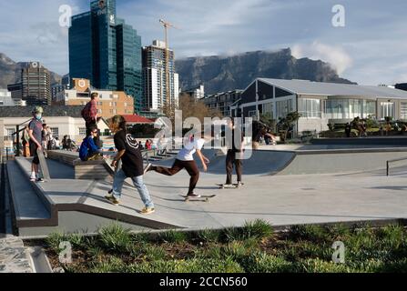 Skater auf ihren Skateboards im öffentlichen Skatepark im V&A Battery Park mit Tafelberg im Hintergrund in Kapstadt, Südafrika. Stockfoto