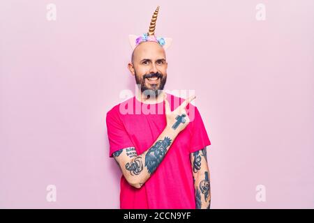 Junger schöner Mann trägt Einhorn Diadem lächelnd fröhlich zeigen mit Hand und Finger zur Seite Stockfoto