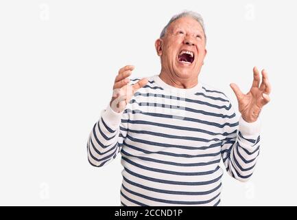 Senior stattlich grauhaarige Mann trägt lässig gestreiften Pullover verrückt und verrückt schreien und mit aggressivem Ausdruck und Arme angehoben. Frustration Stockfoto