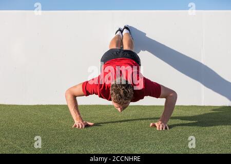 Push-up Fitness-Mann Training mit Wand tun Rückgang Push-up im Fitnessstudio im Freien. Männlicher Fitness-Athlet macht fortgeschrittene Liegestütze auf dem Rasen Park Stockfoto