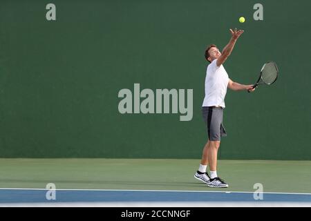 Tennis Serve Spieler Mann serviert Ball während des Spielpunktes auf Outdoor Green Court. Sportler spielen Sport Spiel Training tun Übung Stockfoto