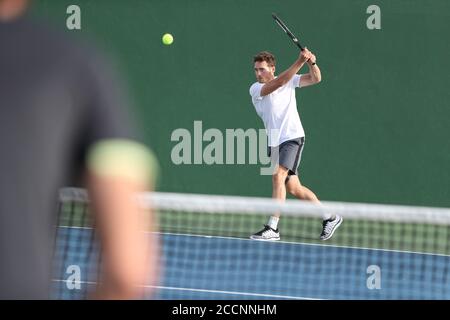 Tennisspieler Mann schlagen Rückhand Ball mit Schläger auf grünem Hintergrund. Sportmänner spielen zusammen auf dem Platz im Freien Stockfoto