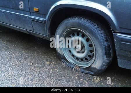 Altes Auto mit Reifenpanne auf der Straße, Nahaufnahme Stockfoto