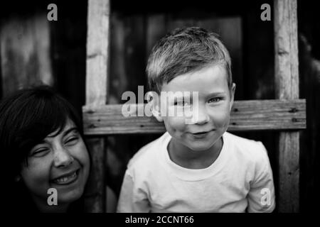 Schwarz-Weiß-Porträt des kleinen Jungen spielt mit seiner älteren Schwester im Freien. Stockfoto