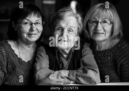 Schwarz-Weiß-Porträt einer alten Frau mit zwei erwachsenen Töchtern. Stockfoto