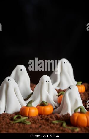 Sugar Paste Szene von halloween, Gruppe von Geistern in einem Kürbis Patch, Schokoladenkuchen Boden, dunkle strukturierte Hintergrund, Copy Space Stockfoto