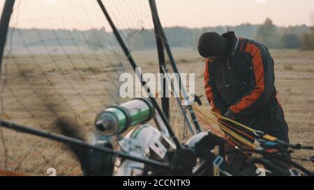 Mann, der sich auf das Paramotorgliding vorbereitet. Paramotor und Sicherheitsgetriebe prüfen. Hochwertige Fotos Stockfoto