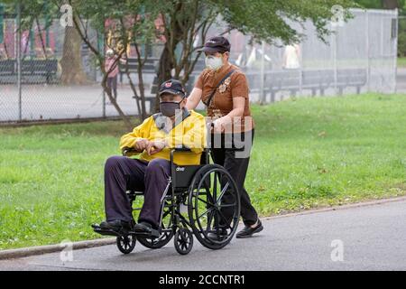 Ein asiatischer Amerikaner und sein Begleiter, beide mit chirurgischen Masken, im Kissena Park in Flushing, Queens, New York City. Stockfoto