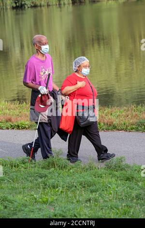 Ein blinder Mann und sein Begleiter auf einem frühmorgendlichen Übungsspaziergang in der Nähe des Sees im Kissena Park, Queens, New York City. Stockfoto