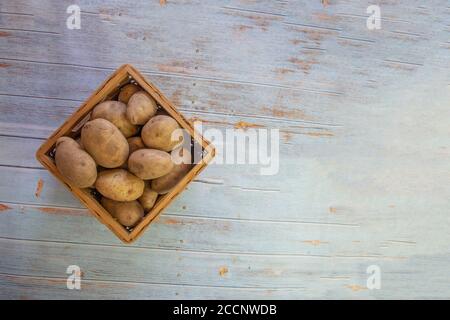 Frisch geerntete Bio-Kartoffeln im Korb. Auf alten Brettern Stockfoto