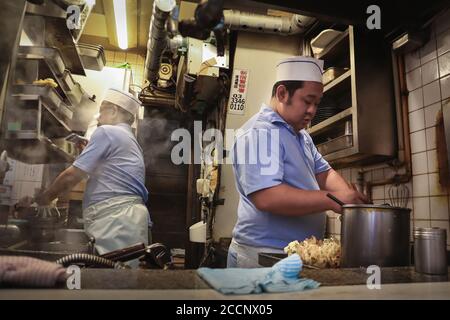 Zwei Köche bereiten am Straßenstand bei Nacht Essen zu. Shop serviert köstliche Tempura und Nudeln Suppe. Omoide Yokocho, Shinjuku, Tokio, Japan, Asien Stockfoto