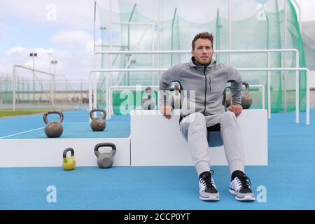 Gym Fitness Mann Training Arme Muskeln tun Trizeps Dips im Outdoor-Trainingszentrum im Stadion. Sportlerin in Jogginghosen Sportswear draußen Stockfoto