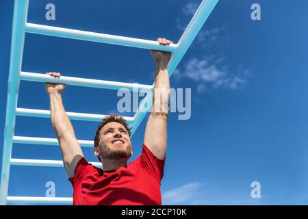 Fitness Monkey Bars Mann Training Arme Muskeln im Dschungel Fitnessstudio im Freien im Sommer. Athlet trainieren Greifen Klettern auf Leiter Ausrüstung beim Sport Stockfoto