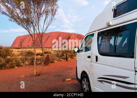 Urlaub in Australien. Weißes Wohnmobil ohne Logos, geparkt mit Blick auf den Mount Uluru. Mittelgroßer Wohnwagen, Platz für zwei Personen mit Küche innen. Stockfoto