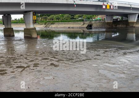 Trockener Flussboden ist sichtbar, da der Wasserstand im Saigon-Fluss abgesenkt wird. Wasserpegelmarkierungen an den Brückenstützen. Sommertrockenheit in Ho Chi M. Stockfoto