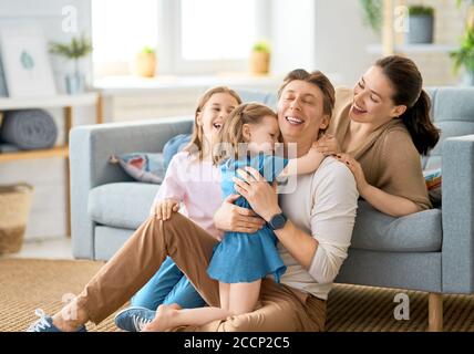 Alles gute zum Vatertag! Zwei Kinder Töchter mit Mutter gratulieren Papa. Mama, Papa und Mädchen lachen und umarmen. Familienurlaub und Zweisamkeit. Stockfoto