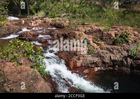 Leute, die Getränke trinken und sich im Wasser entspannen. Wasserfälle und natürliche Pools in Buley Rockholes, Litchfield, Northern Territory, Australien Stockfoto