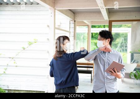 Mann und Frau machen einen Ellenbogen Bump Gruß ohne Berühren Ihrer Hände Stockfoto