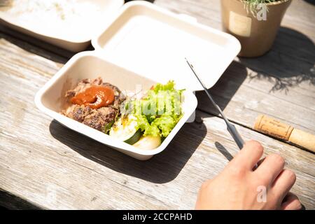 Reifer Mann, der auf der Terrasse ein Take-out-Mittagessen isst Stockfoto