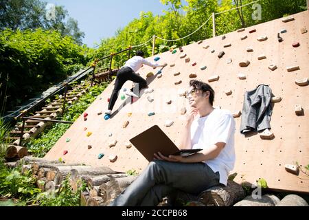 Geschäftsleute, die vor der Kletterwand arbeiten und Bouldering genießen Stockfoto