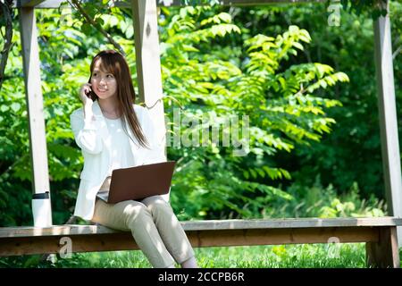 Junge Frau, die unter der Pergola arbeitet Stockfoto