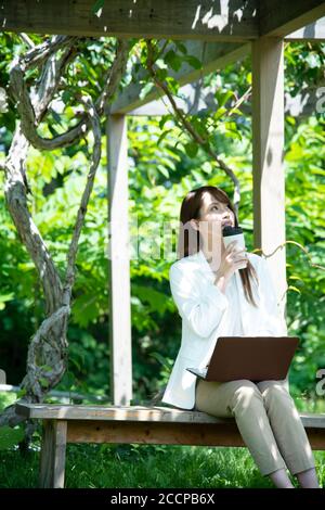 Junge Frau, die unter der Pergola arbeitet Stockfoto