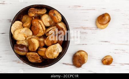 Knusprig gebratene Saubohnen mit Salz in einer Schüssel Nahaufnahme auf einem Tisch. Vicia faba. Selektiver Fokus Stockfoto