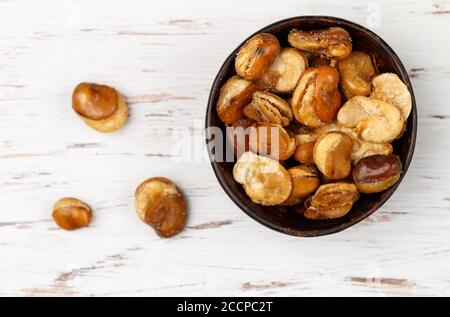 Knusprig gebratene Saubohnen mit Salz in einer Schüssel Nahaufnahme auf einem Tisch. Vicia faba. Selektiver Fokus Stockfoto