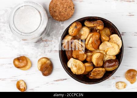 Knusprig gebratene Saubohnen mit Salz in einer Schüssel Nahaufnahme auf einem Tisch. Vicia faba. Selektiver Fokus Stockfoto