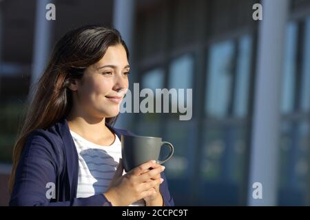 Frau trinkt Kaffee auf einer Terrasse mit Blick auf eine sonnige Tag Stockfoto