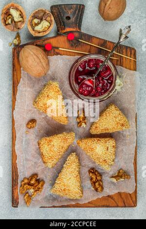 Gegrillter oder gebackener Camembert- oder Brie-Käse. Köstliche Vorspeise in Sesampanade. Serviert mit Walnüssen und Preiselbeere (Preiselbeere, Preiselbeere) Sauce Stockfoto