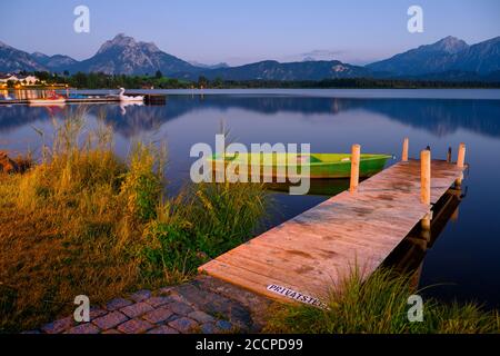 Holzlandesteg am Hopfensee, im Hintergrund die Alpen und das Dorf Hopfen am See, Bayern, Deutschland Stockfoto