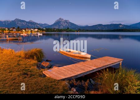 Holzlandesteg am Hopfensee, im Hintergrund die Alpen und das Dorf Hopfen am See, Bayern, Deutschland Stockfoto