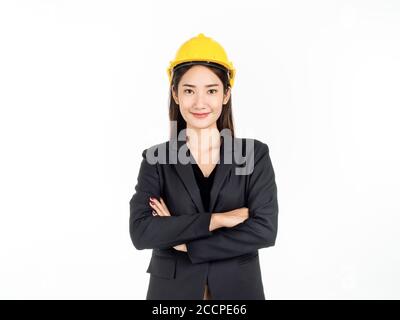 Junge asiatische Geschäftsfrau lächelnd trägt schwarzen Anzug und gelben Schutzhelm stehen mit ihren Armen gefaltet. Porträt einer Ingenieurin suchen confi Stockfoto