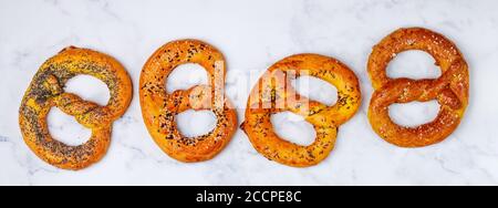 Brezel. Eine Reihe von verschiedenen Brezeln mit schwarzem und weißem Sesam, Mohn, Kümmel oder Kümmel, großes Meersalz. Süße und salzige Vorspeise für Feinschmecker Stockfoto