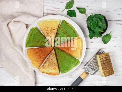 Verschiedene bunte Pfannkuchen. Weizen, Käse und Spinat Crepes in einem weißen Teller auf einem hölzernen Hintergrund. Selektiver Fokus, Draufsicht Stockfoto