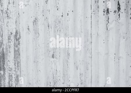 Verzinktes Blech mit weißer Farbe lackiert. Leere weiße Wand Textur Hintergrund. Abblätternde Farbe an der weißen Wand. Verzerrtes graues galvanisiertes Blech. Stockfoto