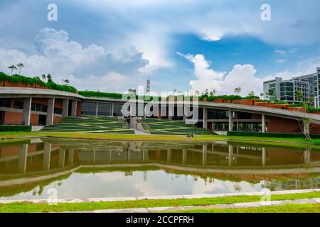 Umweltfreundliches Glasgebäude mit vertikalem Garten in der Stadt. Grüner Baum und Efeu auf nachhaltiges Bauen gegen blauen Himmel und weiße Wolken. Modern Stockfoto