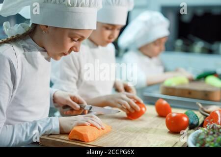 Kinder mahlen Gemüse in der Küche eines Restaurants. Stockfoto