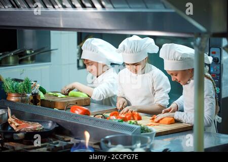 Kinder mahlen Gemüse in der Küche eines Restaurants. Stockfoto