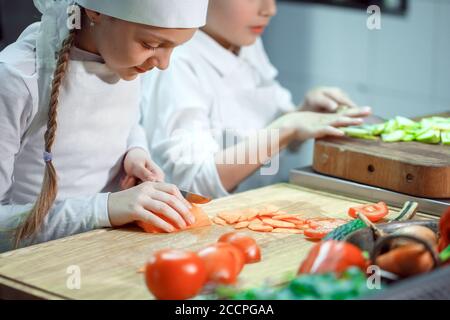 Kinder mahlen Gemüse in der Küche eines Restaurants. Stockfoto