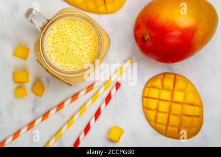 Smoothie oder Milchshake aus frischer Mango, Joghurt oder Milch und Eiswürfeln im Mason-Glas auf einem Marmortisch. Konzept der gesunden Vitamingetränke. Selektiv Stockfoto