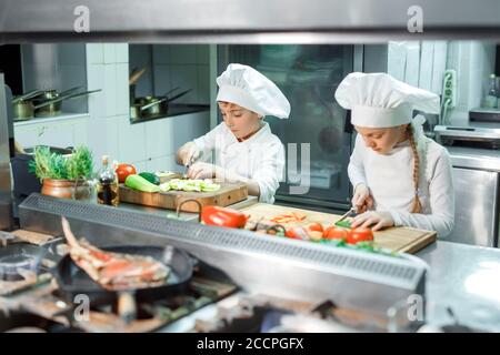 Kinder mahlen Gemüse in der Küche eines Restaurants. Stockfoto